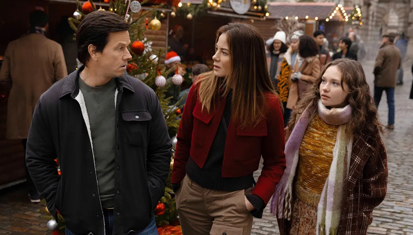 Mark Wahlberg walking through a Christmas market with Michelle Monaghan