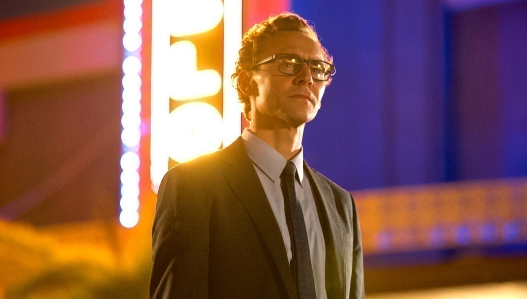 Tom Hiddleston standing in front of a movie theatre in The Life of Chuck