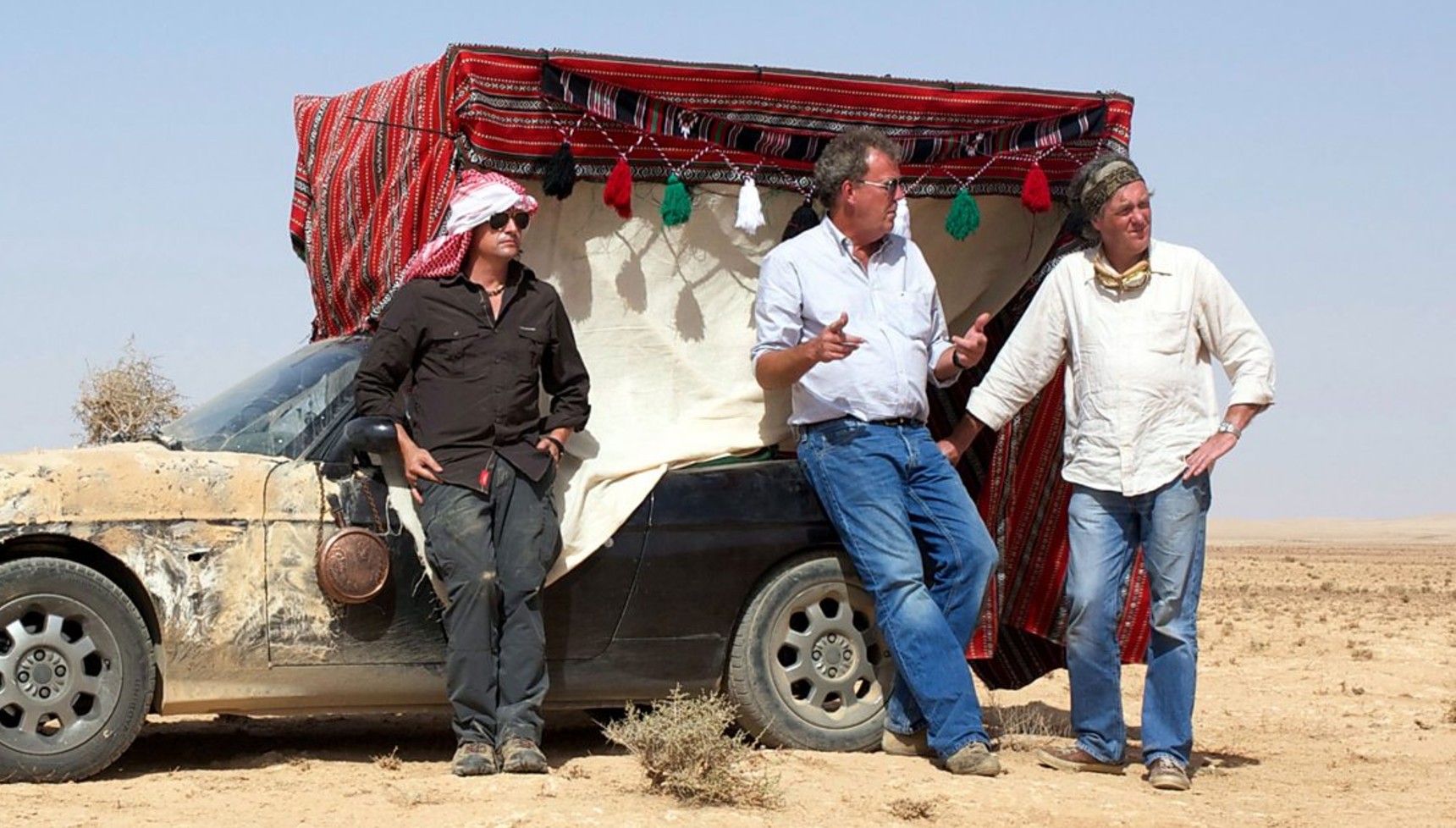 Richard Hammond, Jeremy Clarkson, and James May leaning against a car in the Top Gear Middle East Special