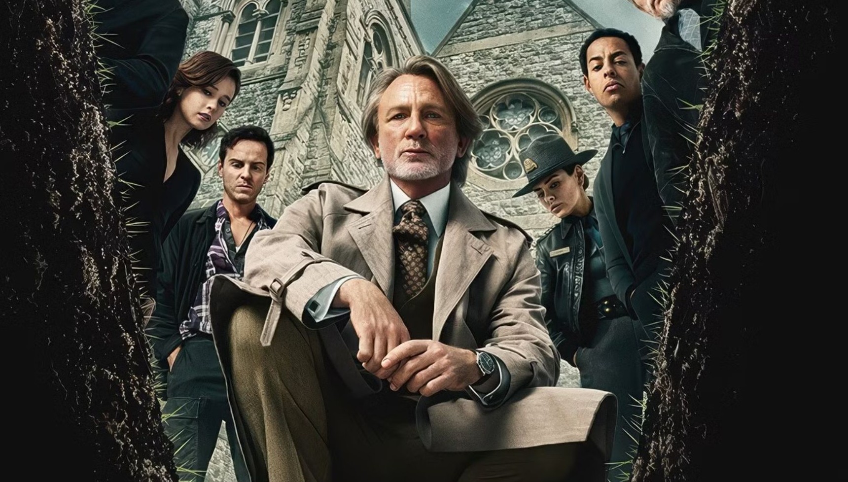 Daniel Craig as Benoit Blanc kneeling down next to other members of the Wake Up Dead Man cast