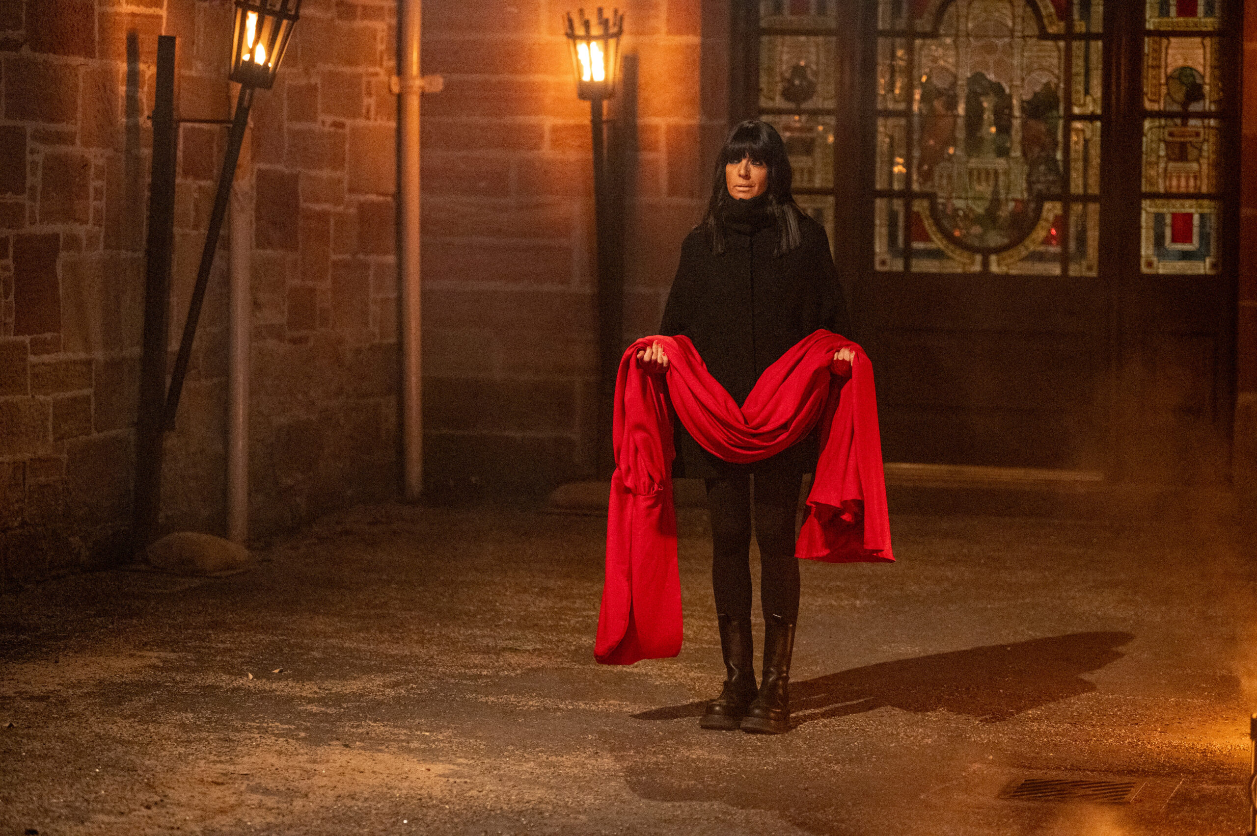Claudia Winkleman holding the red Traitor cloak
