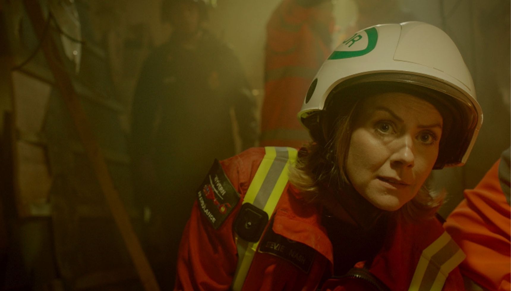 Stevie in protective clothing talking Kim through a medical procedure