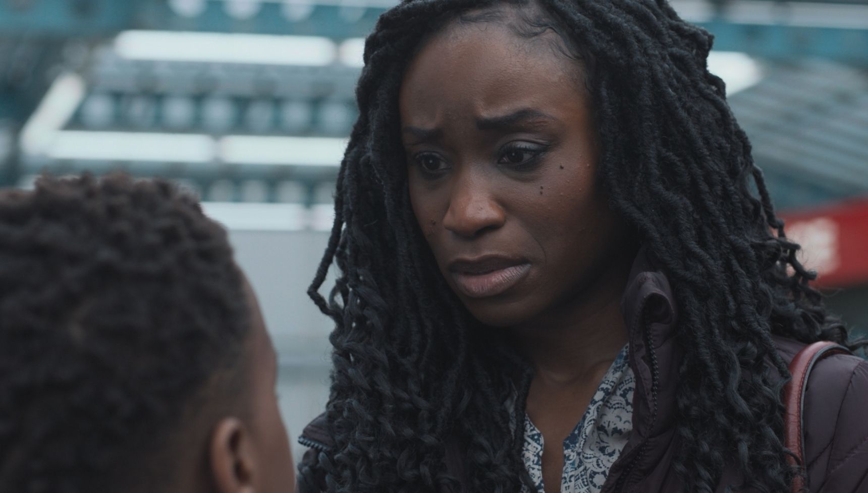 Ngozi looking down at her son with a worried look on her face 