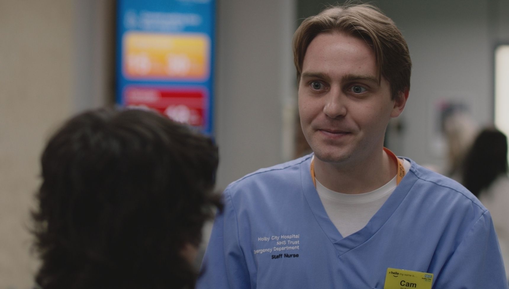 Cam in Casualty in blue scrubs