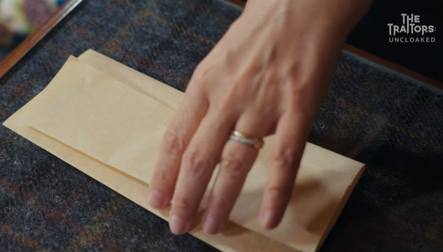 Harriet's hand holding a letter on The Traitors