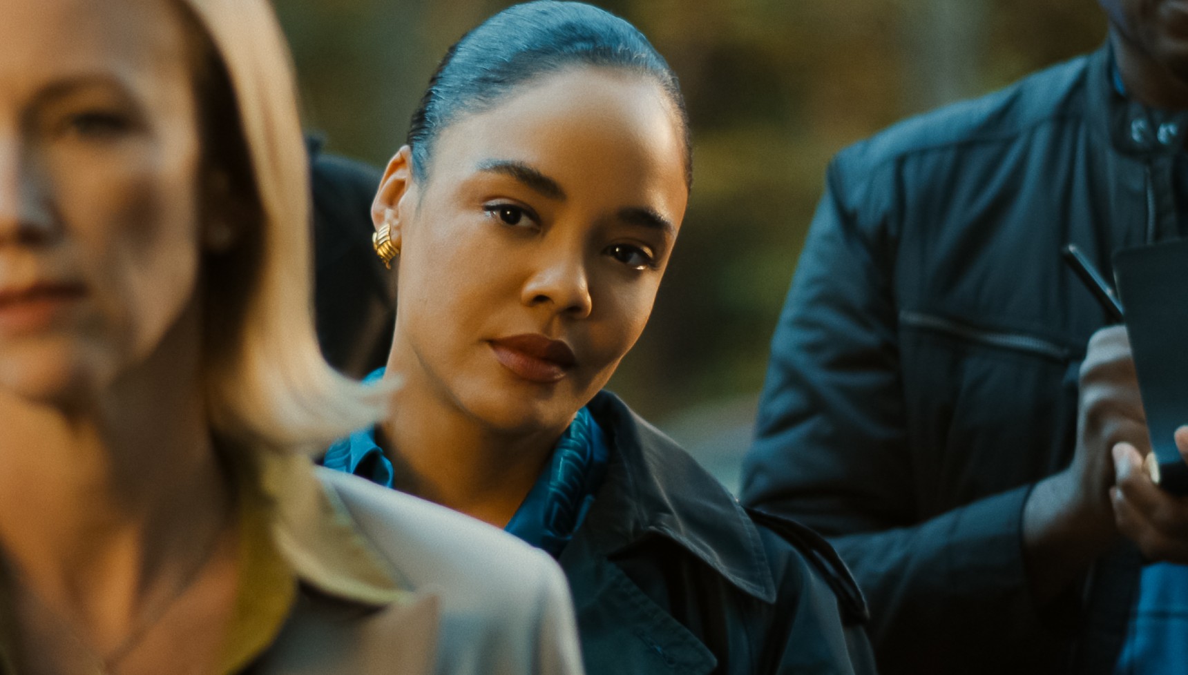 Tessa Thompson peering around someone's shoulder in His and Hers
