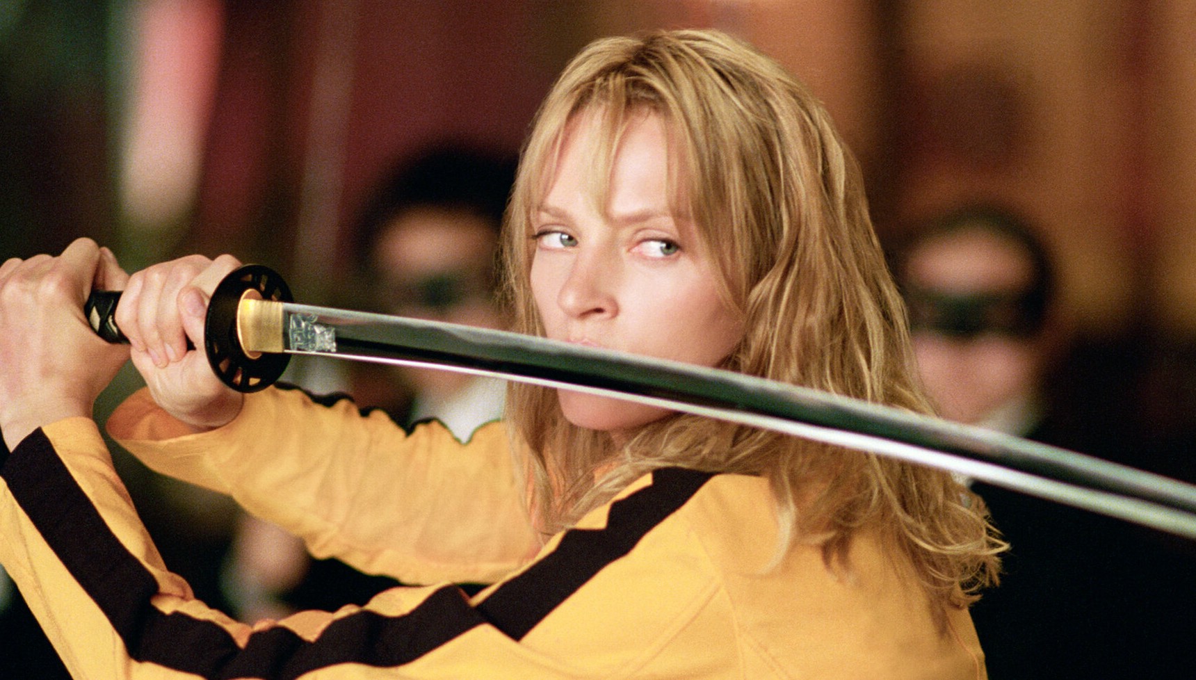 Uma Thurman in a yellow tracksuit holding a sword