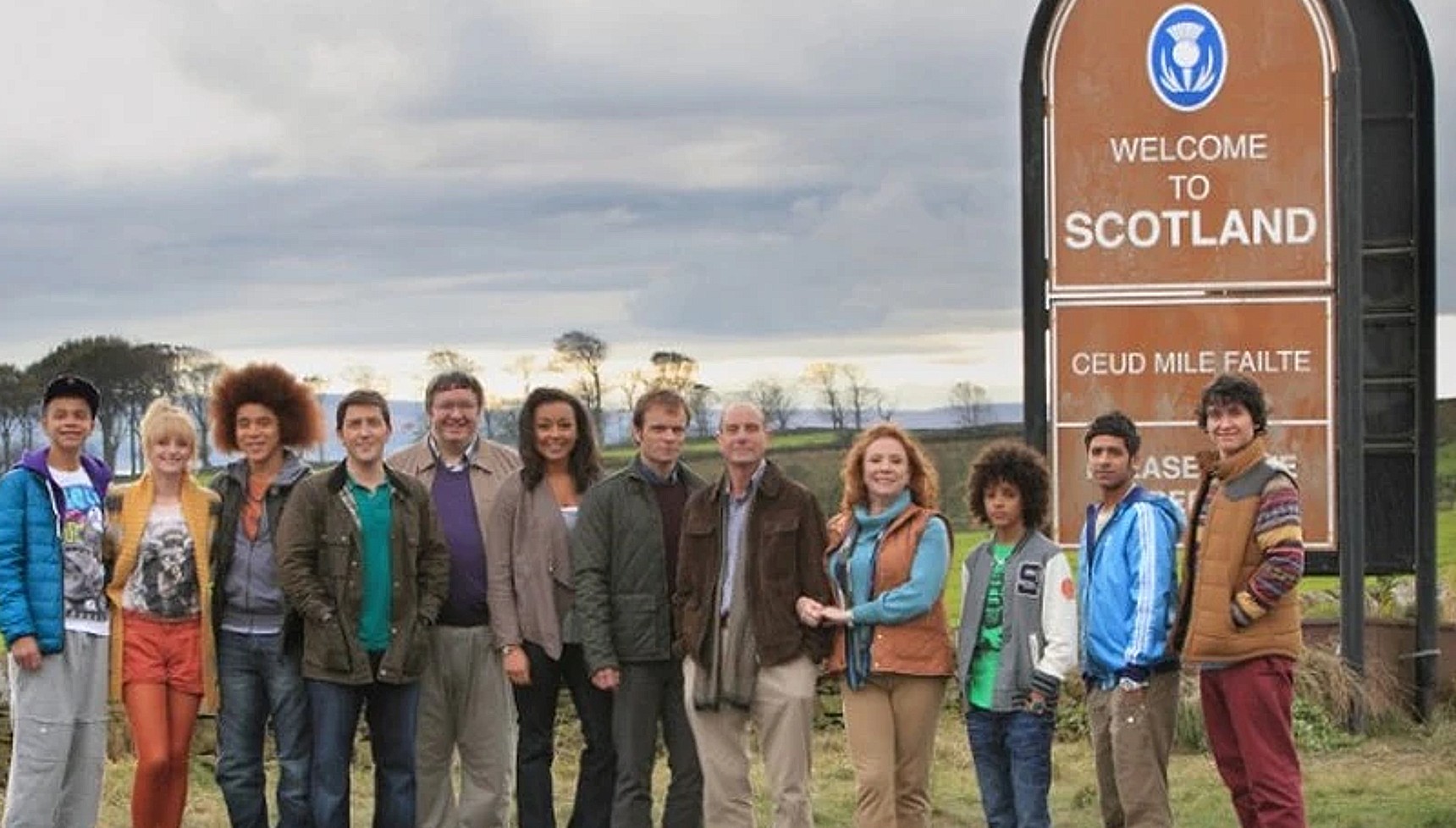 The cast of Waterloo Road next to a Scotland sign