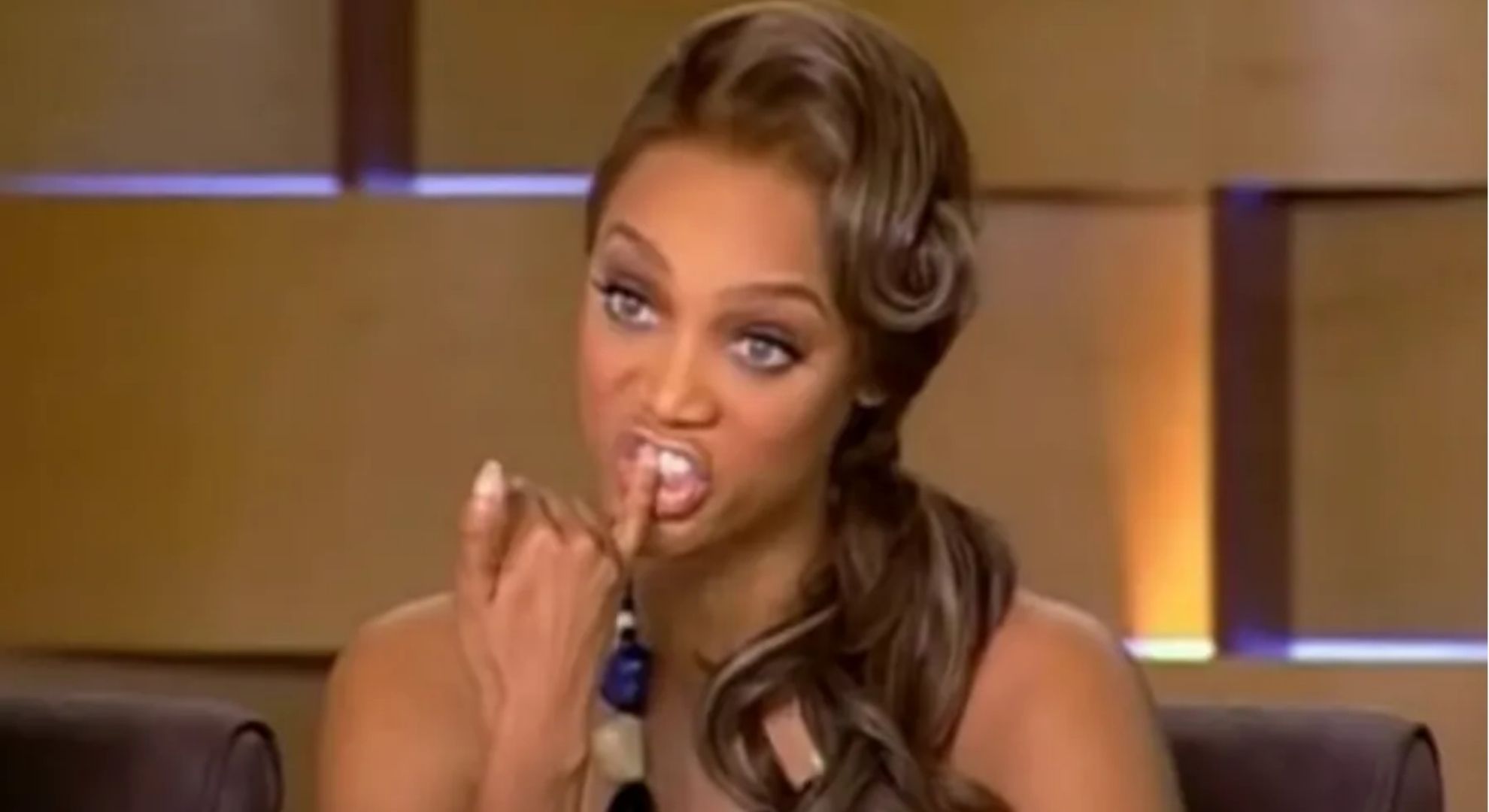 Tyra Banks with finger in front of teeth 
