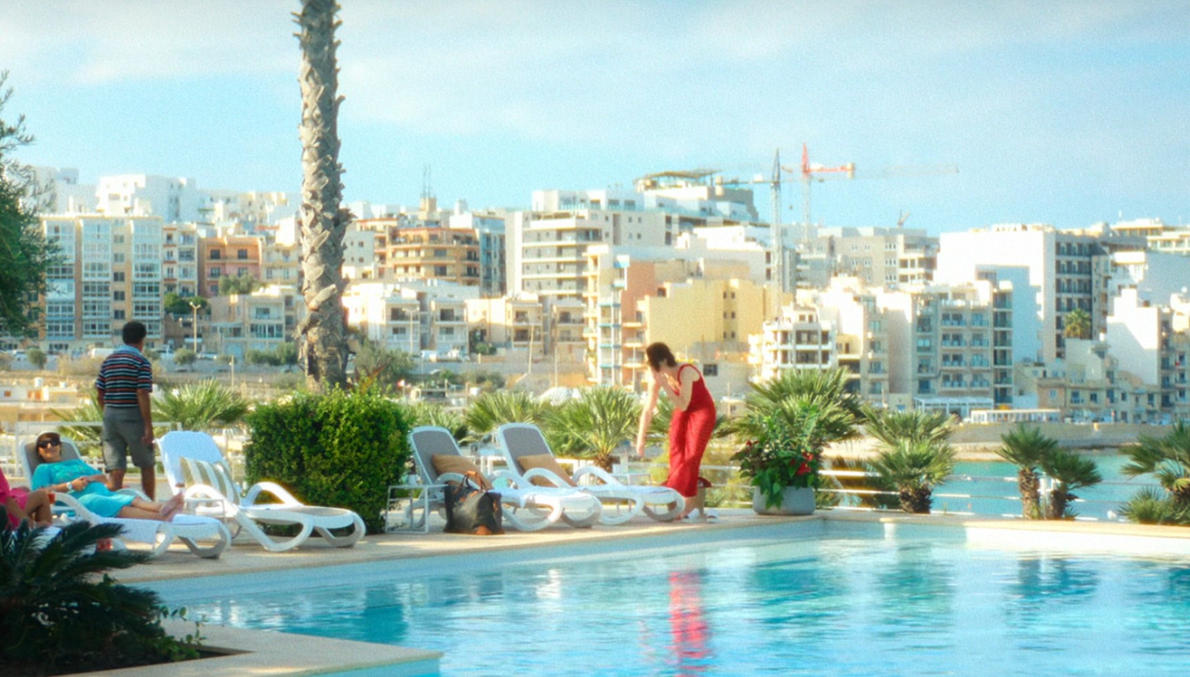 A woman in a red dress at a hotel pool