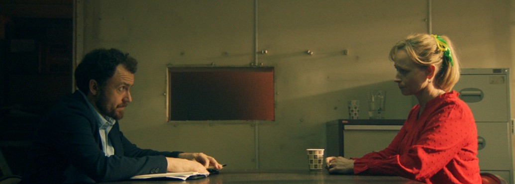 Laura Bayston as Kate McCann and an unknown actor sitting across from each other in Suspect: Kate McCann