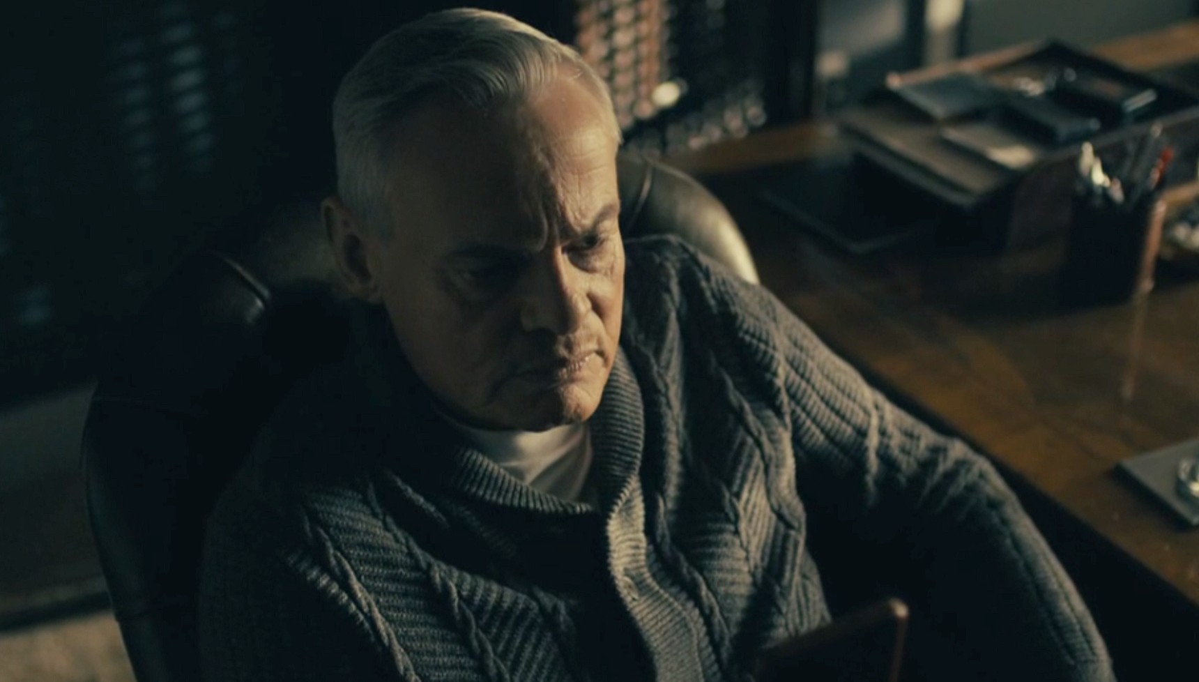 Martin Clunes as Huw Edwards sitting in a chair