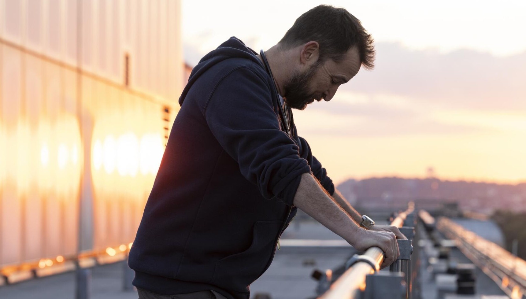 Noah Wyle leaning on a balcony in The Pitt
