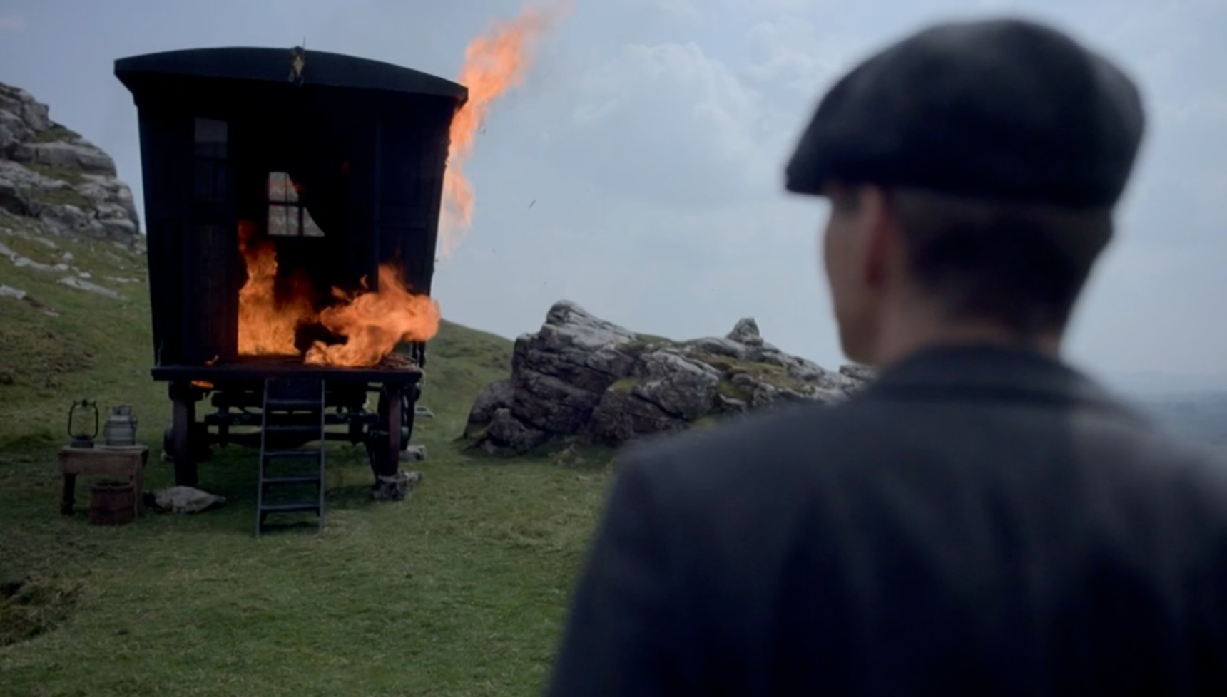 Tommy Shelby looking at a burning wagon in Peaky Blinders
