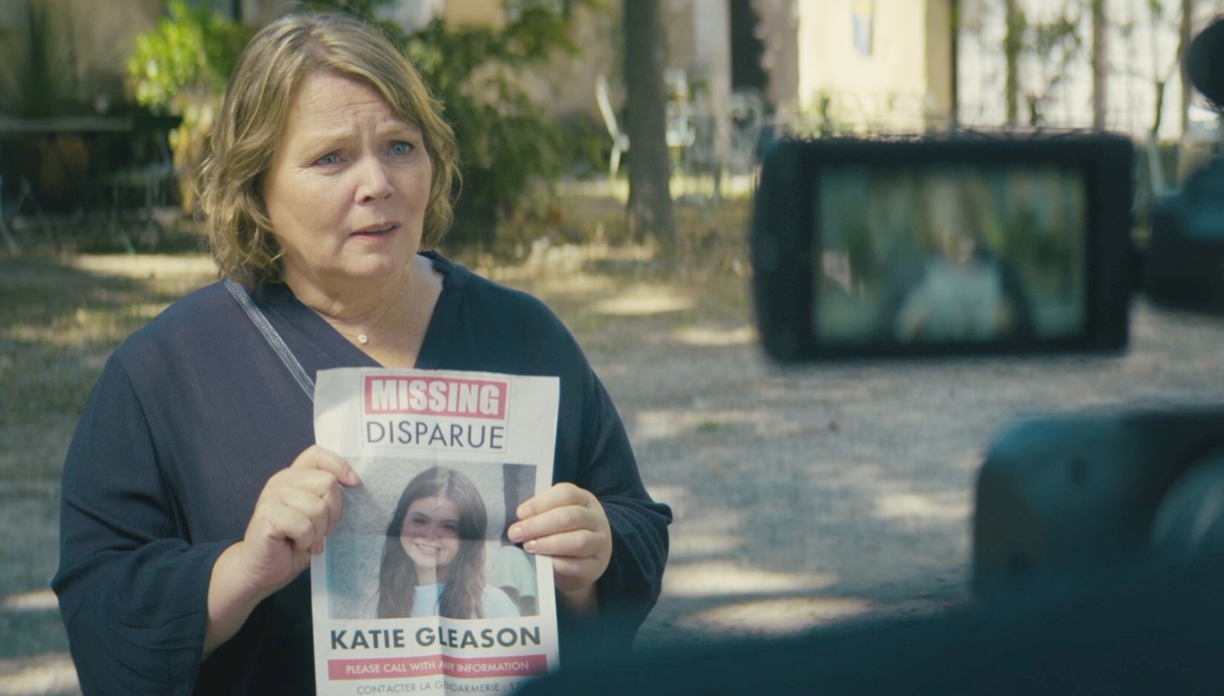 Sarah Gleason holding up a missing poster of her daughter in Missed Call
