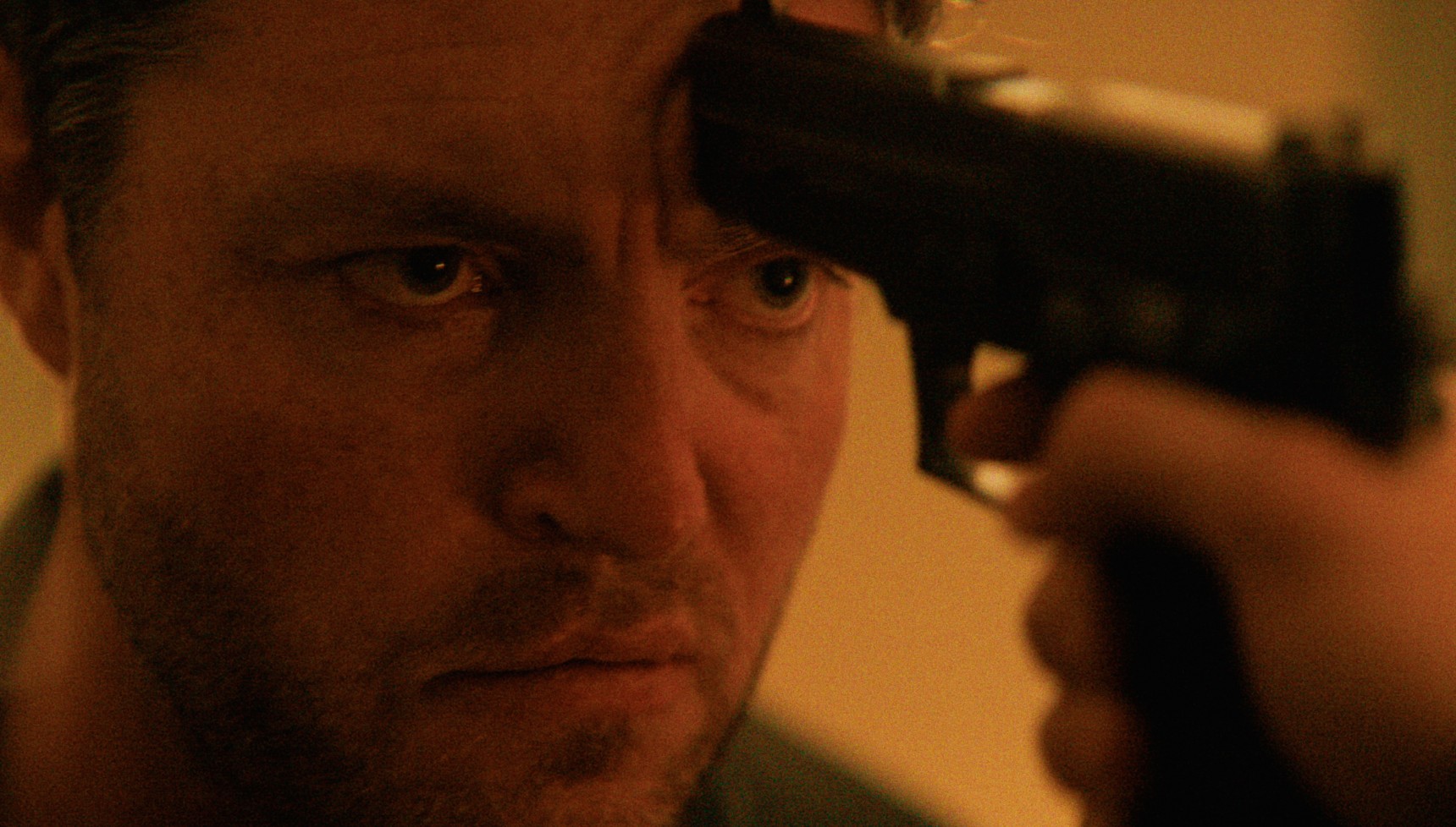 Tom Burke with a gun held at his head in Legends