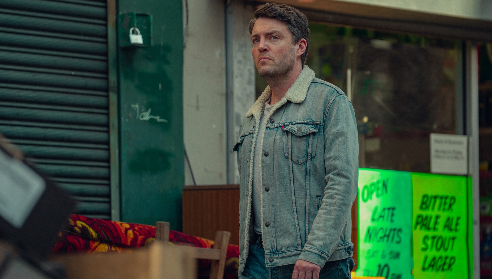 Tom Burke walking along a street in Legends