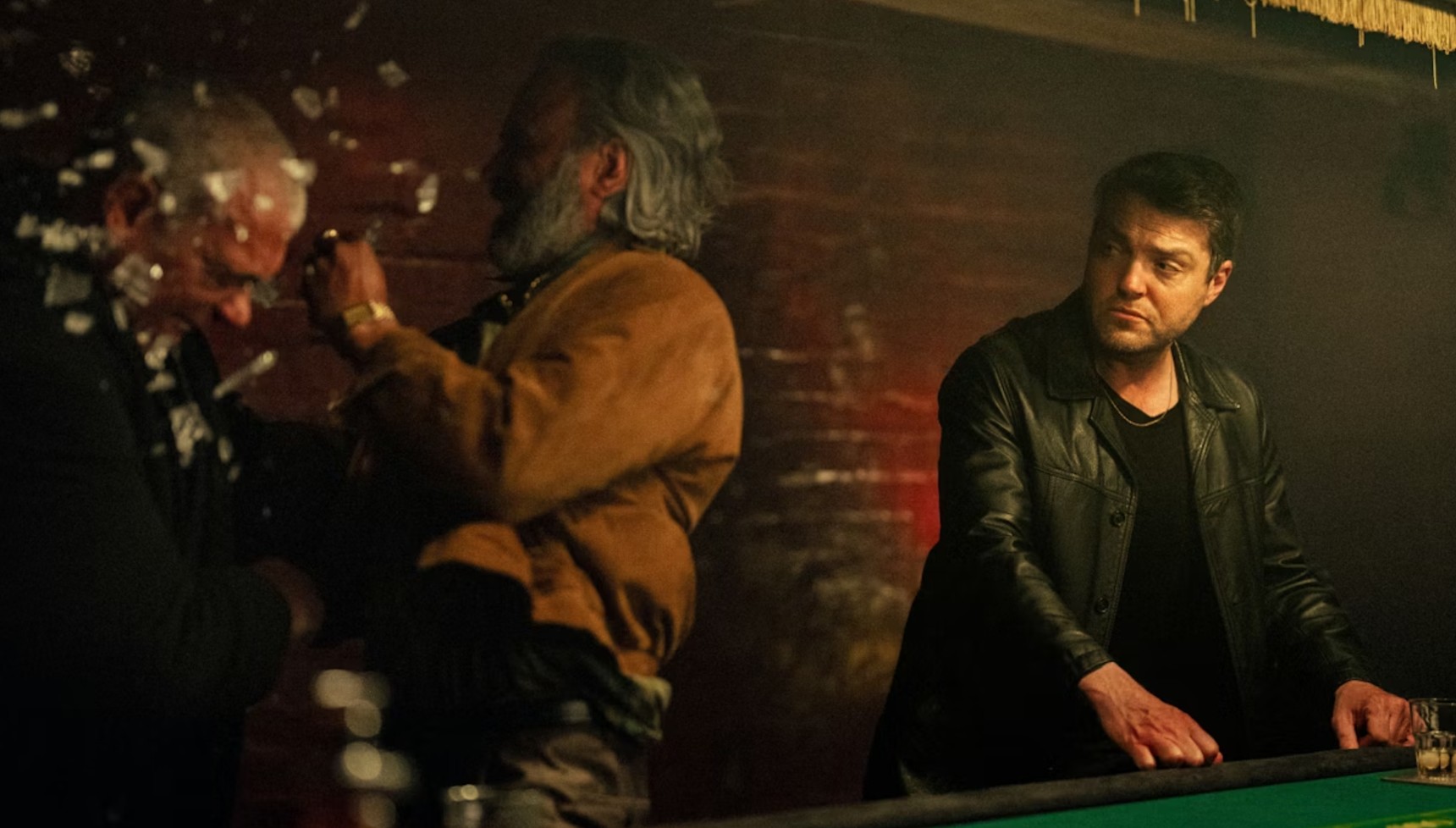 Tom Burke's Guy Stanton looking at a man smashing a glass of someone's head in Legends 