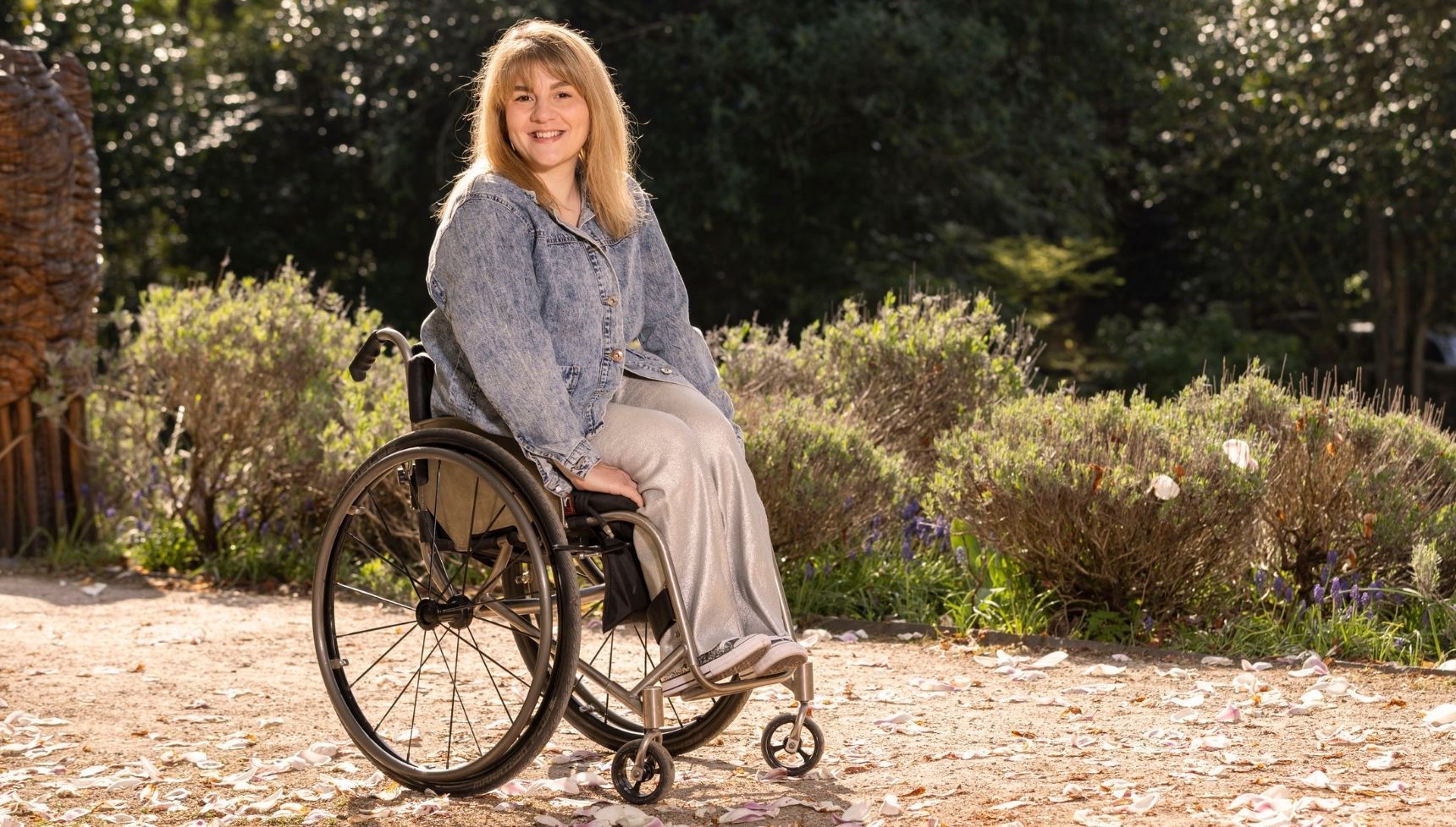 Ruth Madeley in wheelchair in denim shirt and silver trousers 