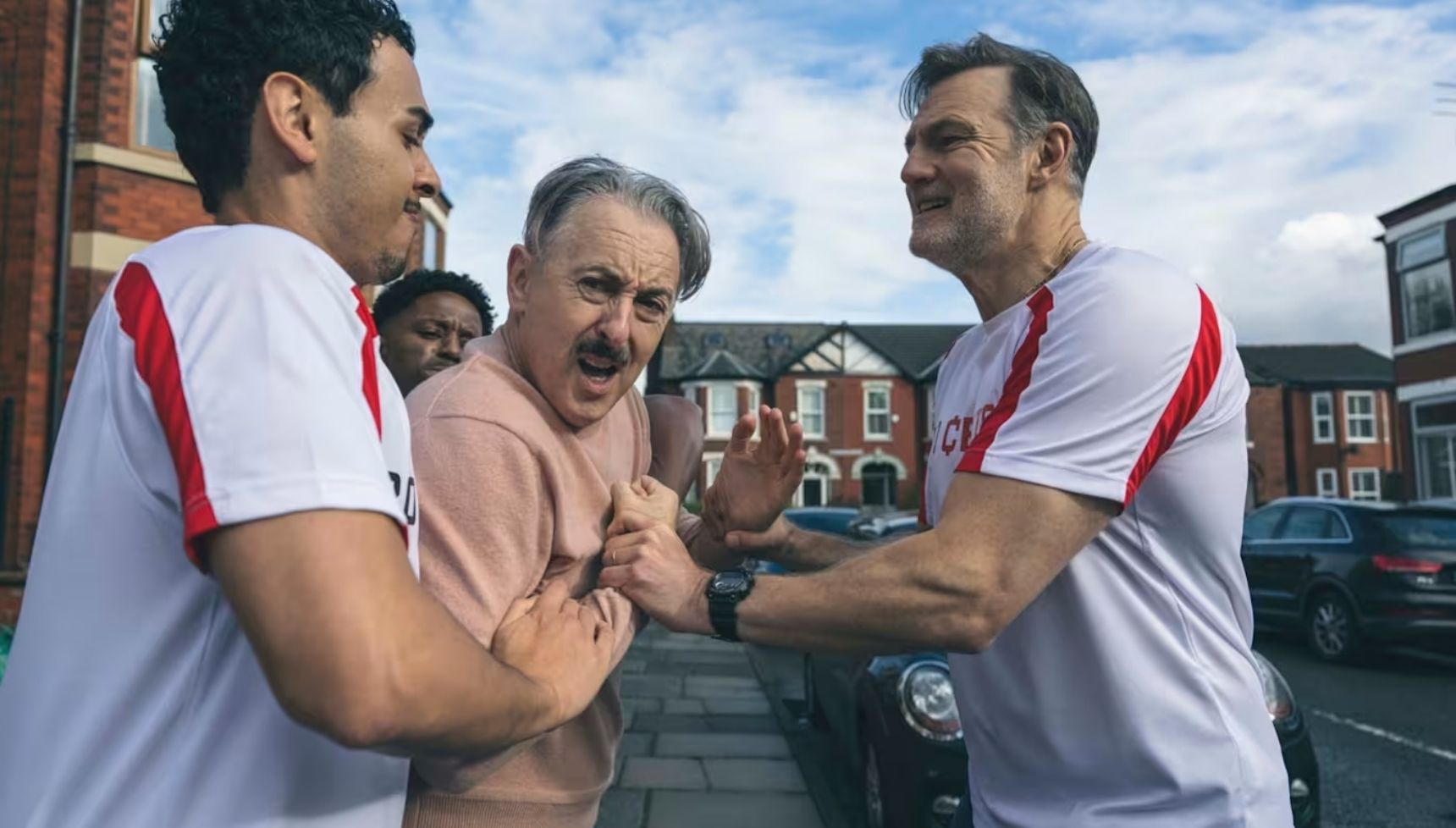 Alan Cumming being held by David Morrissey and other members of the Tip Toe cast