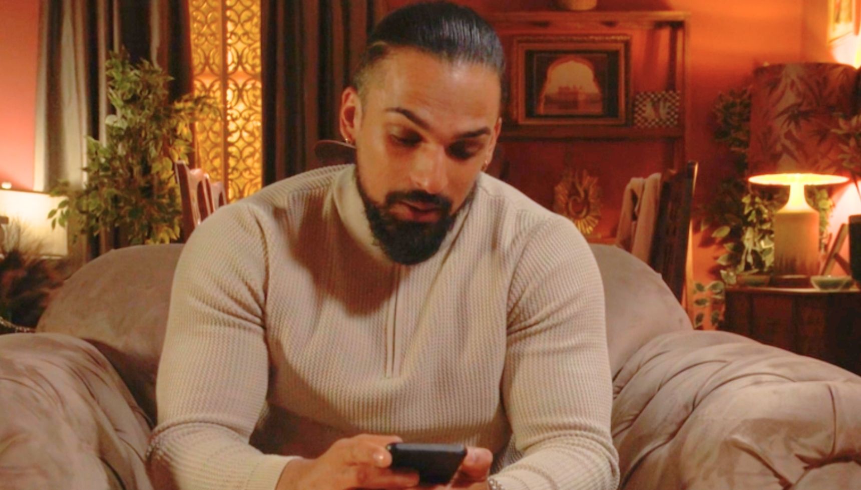 Ravi looking at his phone in EastEnders