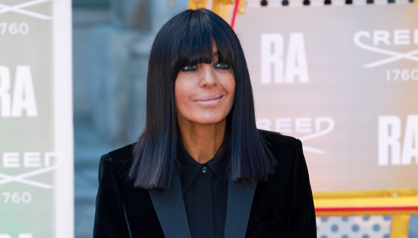 Claudia Winkleman smiling in black suit at event