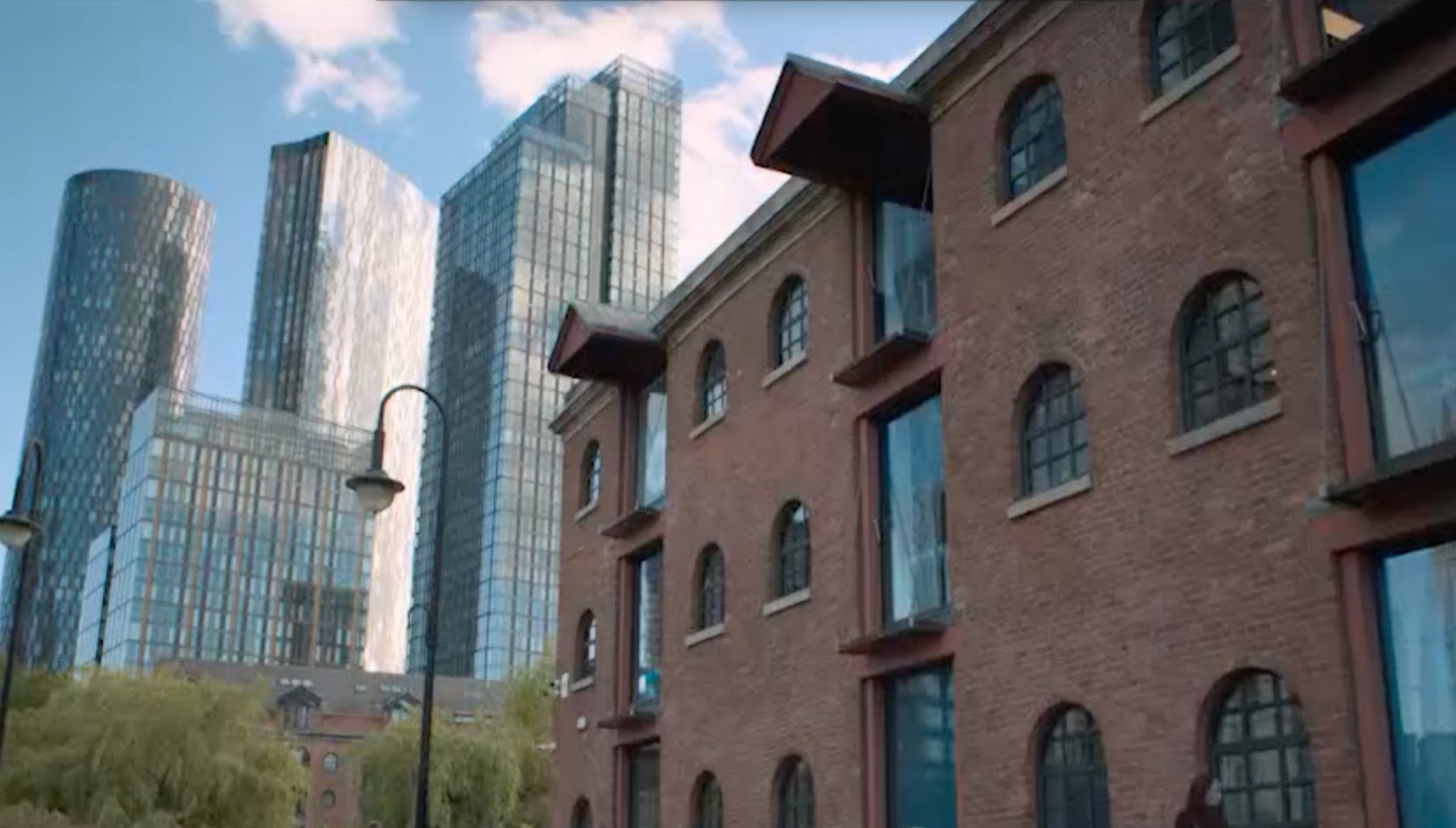 Merchants Warehouse on Castle Street in the Castlefield area of Manchester with modern skyscrapers like the Deansgate Square towers in the background